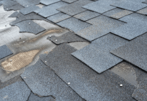 Damaged asphalt shingles on a roof with visible wear and tear, illustrating potential causes of a leaky roof for Silver Spring roofing services.